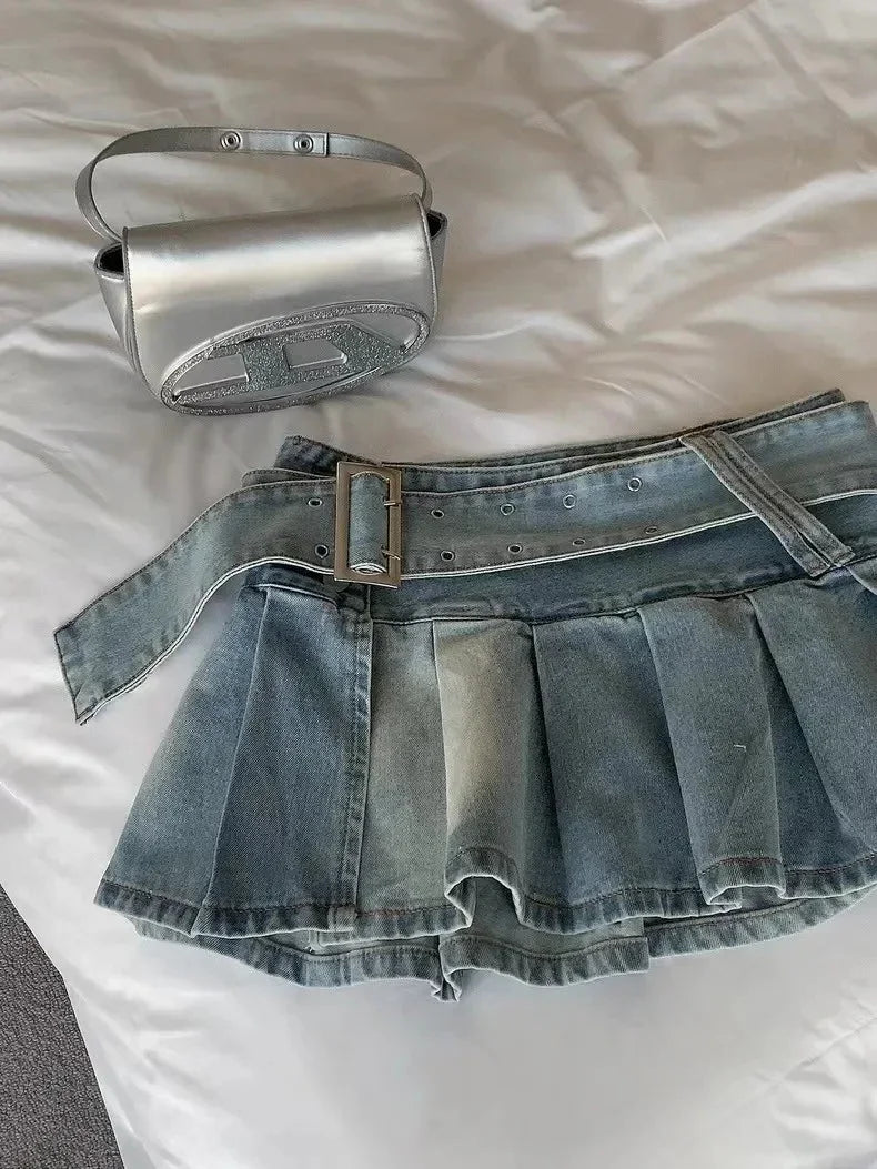 Silver mini handbag with glitter detail and pleated denim mini skirt with belt on white fabric
