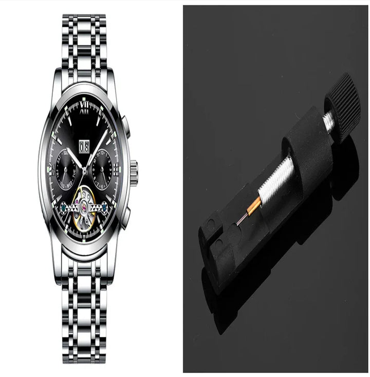 Silver wristwatch with black dial and chronograph beside a black watch spring bar tool