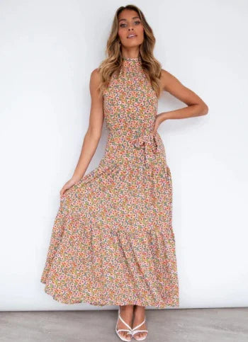 Woman in sleeveless floral maxi dress with high neckline posing against white background