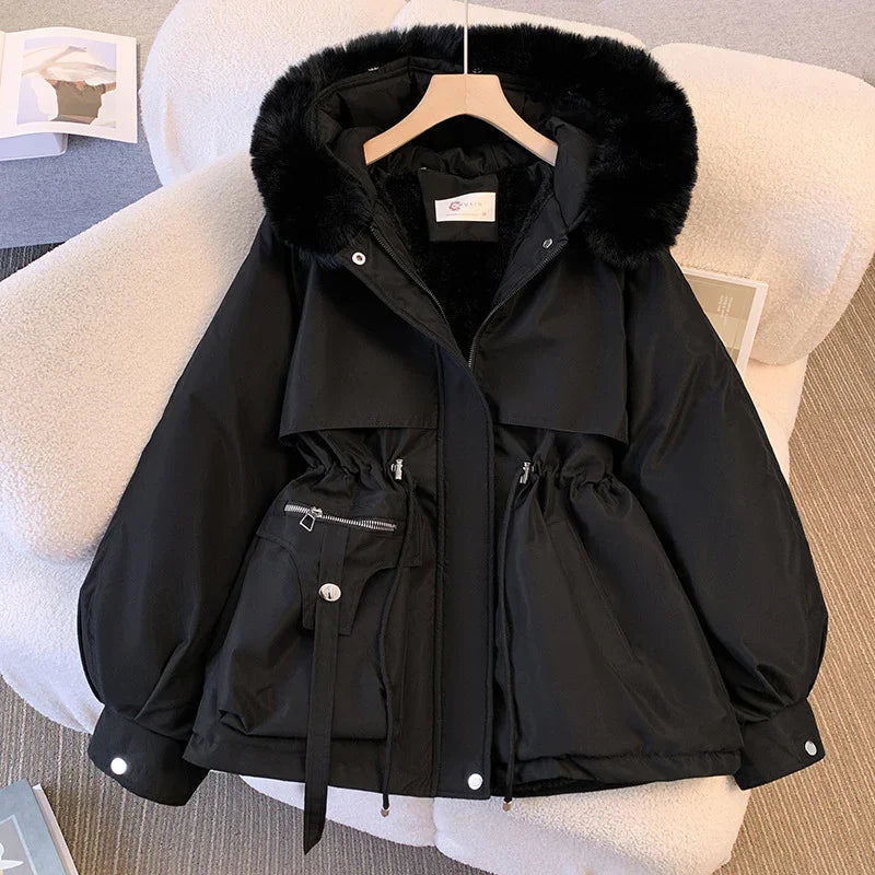 Black winter jacket with faux fur hood, adjustable waist, zipper and snap pockets displayed on white chair