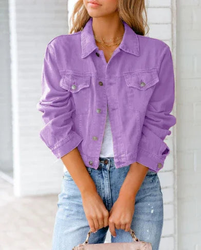 Woman wearing a lavender cropped denim jacket with rolled sleeves and light blue jeans holding a handbag