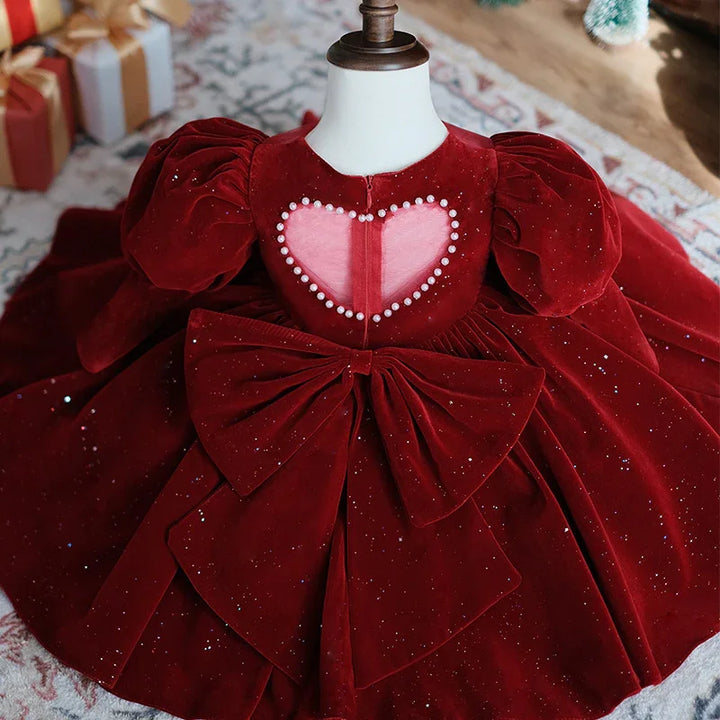 Red velvet toddler dress with puff sleeves, pearl heart cutout, and large bow on skirt