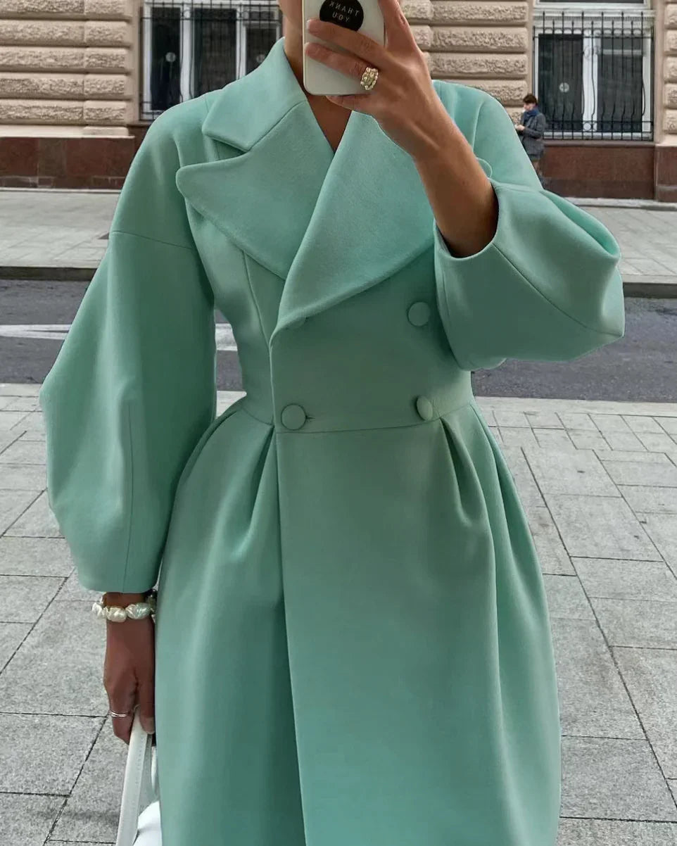 Woman wearing a mint green double-breasted coat with puffy sleeves and wide lapels, holding a white bag on city street