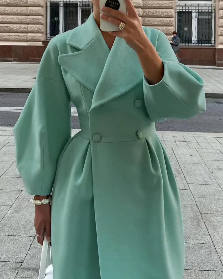 Woman wearing a mint green double-breasted coat with puffy sleeves and wide lapels, holding a white bag on city street