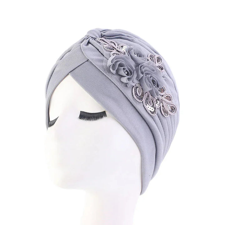 Light gray fabric turban with floral lace and sequin embellishments on white mannequin