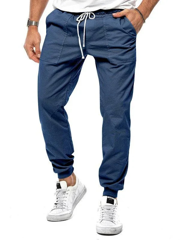 Mens navy blue jogger pants with white drawstring and white sneakers on white background