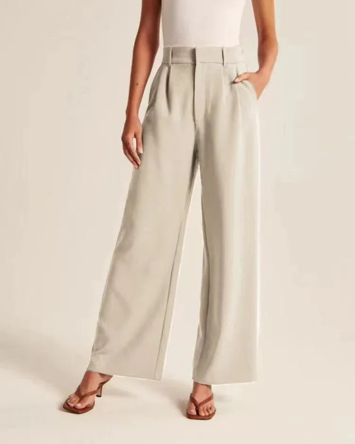Woman wearing beige wide-leg pants with high waist and pleats, paired with brown heeled sandals
