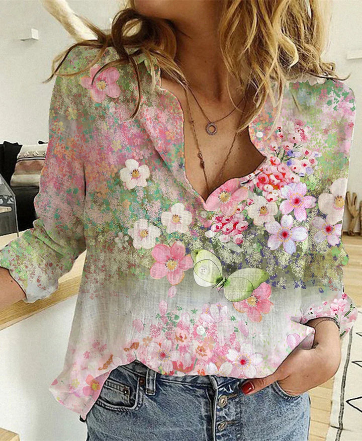 Woman wearing floral print blouse with pink, white flowers and green butterfly, paired with blue jeans