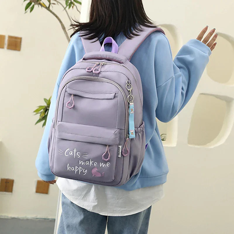 Person wearing pastel purple backpack with cat-themed design and text 'Cats make me happy'