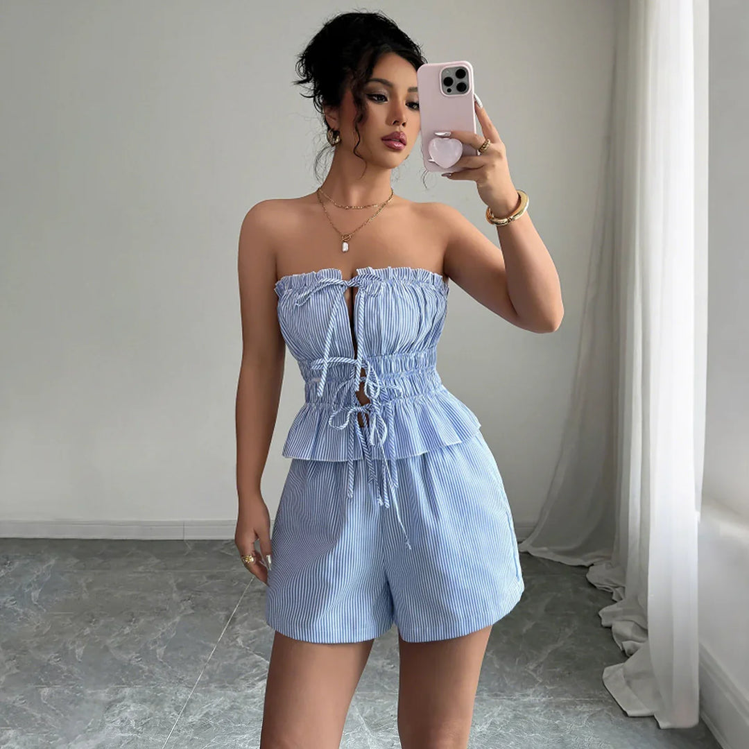 Woman taking selfie wearing blue and white striped strapless peplum top and matching shorts indoors