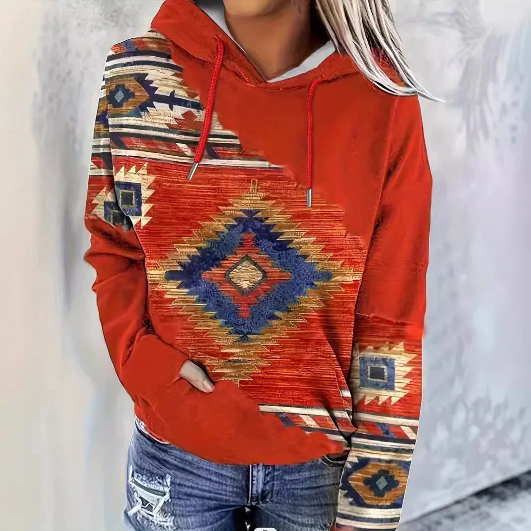 Woman wearing rust red hoodie with southwestern geometric pattern and distressed blue jeans
