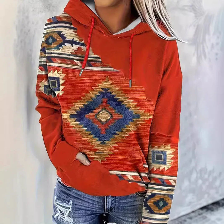 Woman wearing rust red hoodie with southwestern geometric pattern and distressed blue jeans