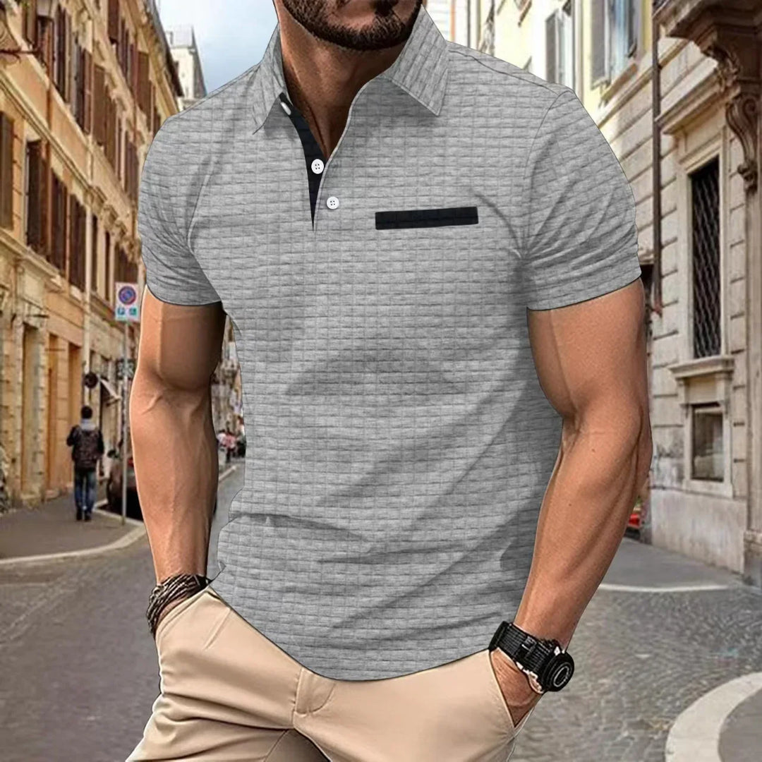 Man wearing light gray textured polo shirt with black buttons and pocket detail in urban street