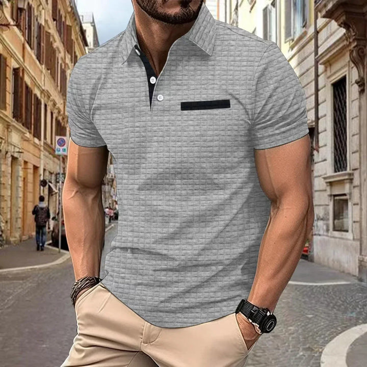 Man wearing light gray textured polo shirt with black buttons and pocket detail in urban street