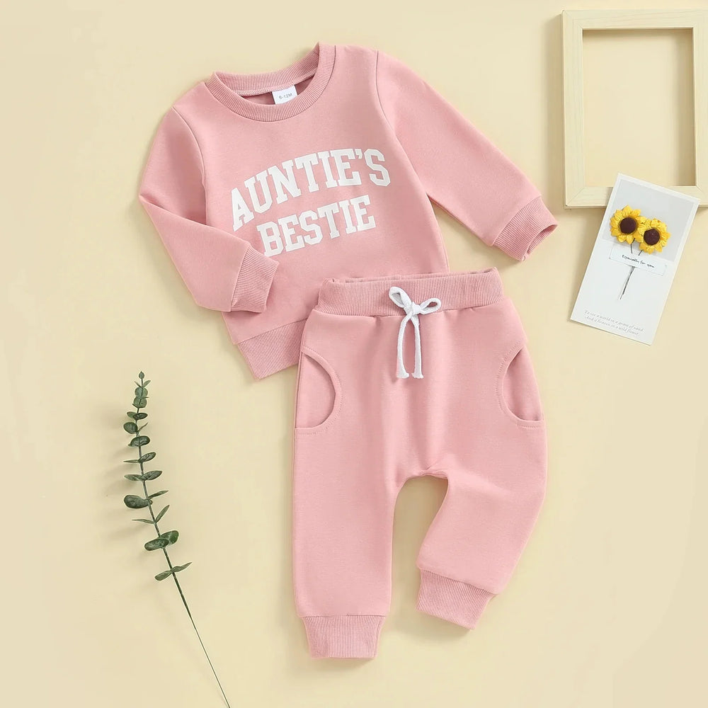 Pink baby outfit with sweatshirt saying Auntie's Bestie and matching jogger pants on beige background