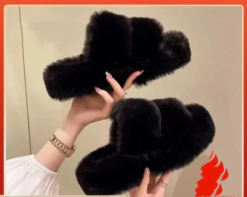 Hands holding a pair of black fluffy cross-shaped slippers against a beige background