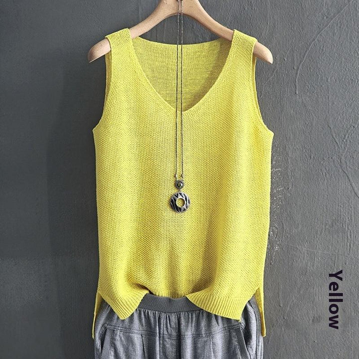 Yellow knitted sleeveless sweater paired with gray pants and pendant necklace on wooden hanger