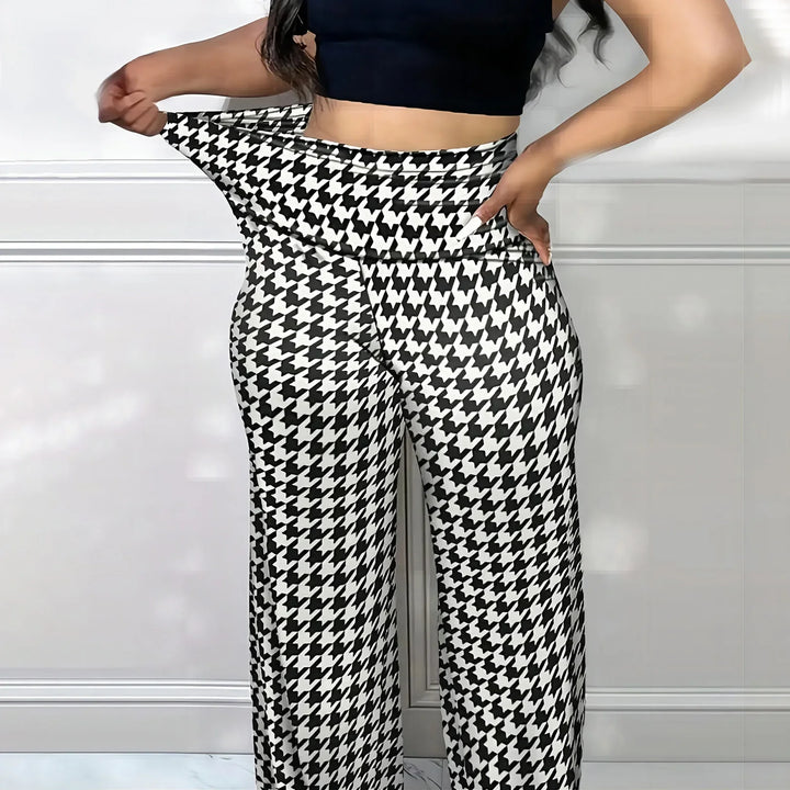 Woman wearing black and white houndstooth patterned wide-leg pants and black crop top, demonstrating stretch fit