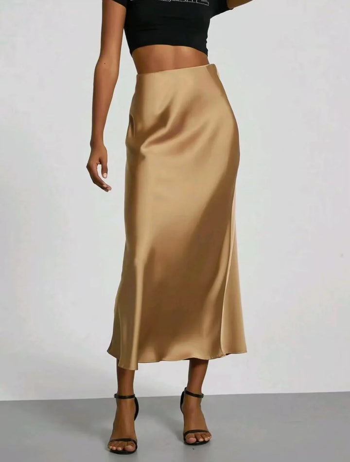 woman wearing a beige satin midi skirt with black ankle-strap heels and a cropped black top