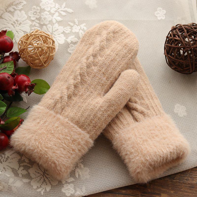 Cozy beige knitted mittens with fluffy cuffs on lace fabric, decorated with wicker balls and red berries