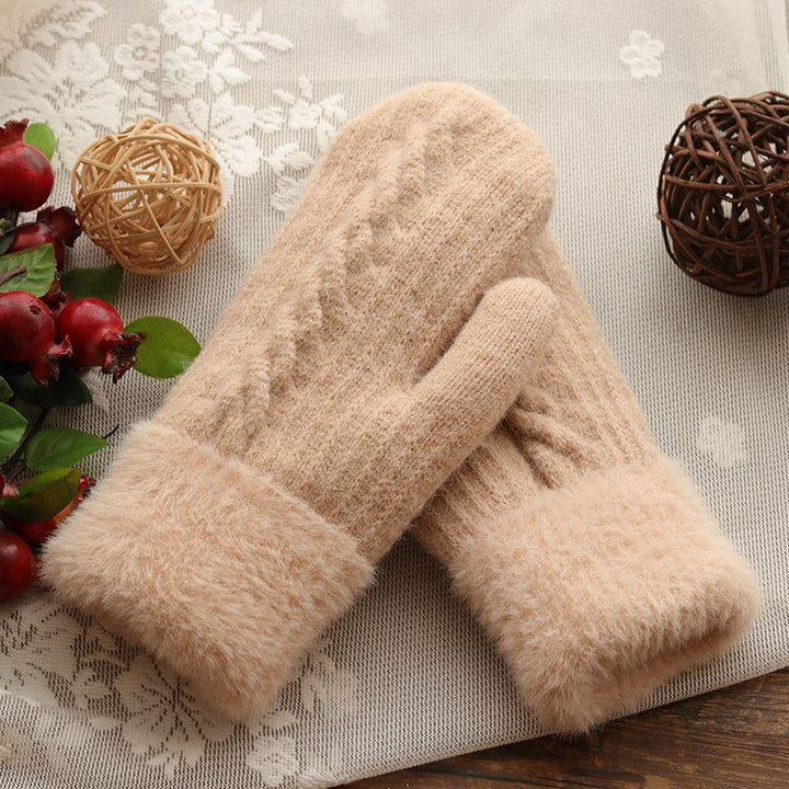 Cozy beige knitted mittens with fluffy cuffs on lace fabric, decorated with wicker balls and red berries