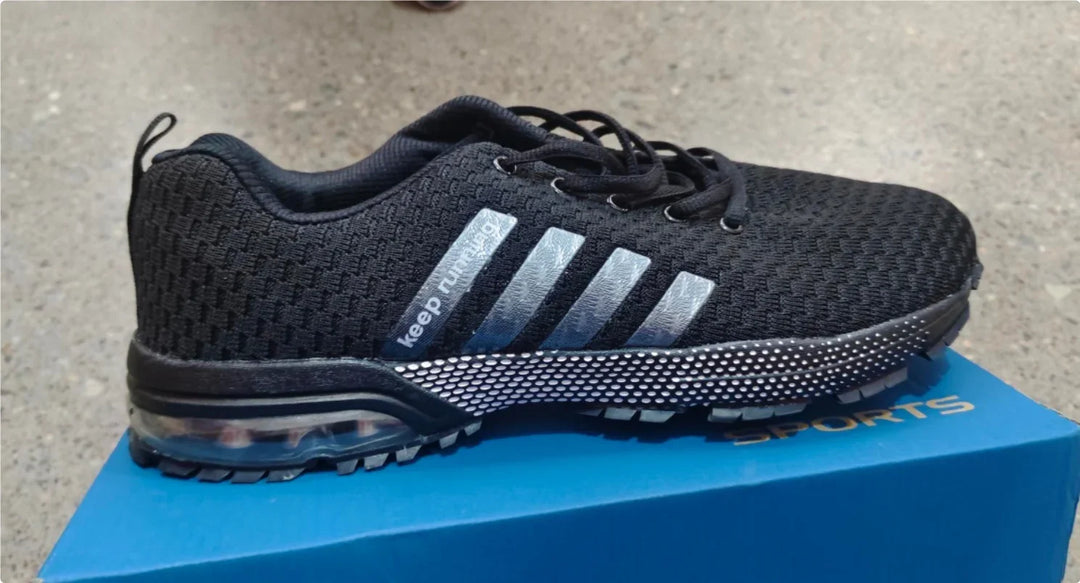 Black sports running shoe with mesh fabric and air cushion sole on blue box