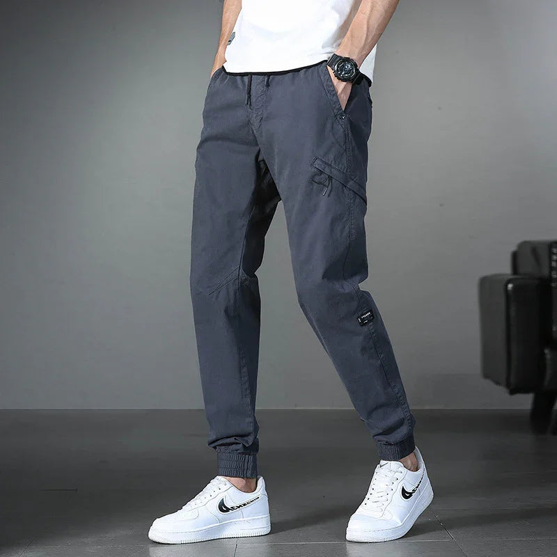 Men's casual dark gray cargo jogger pants paired with white sneakers and a white t-shirt