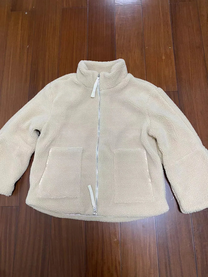 Beige soft fleece zip-up jacket with stand collar and front pockets on wooden floor