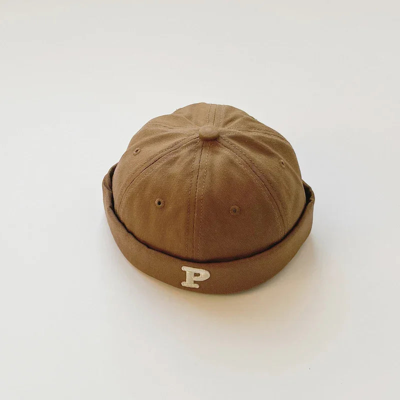 Brown cotton beanie hat with a rolled brim and white letter P on a white background