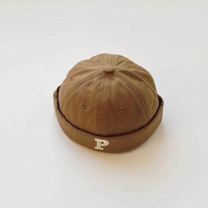 Brown cotton beanie hat with a rolled brim and white letter P on a white background