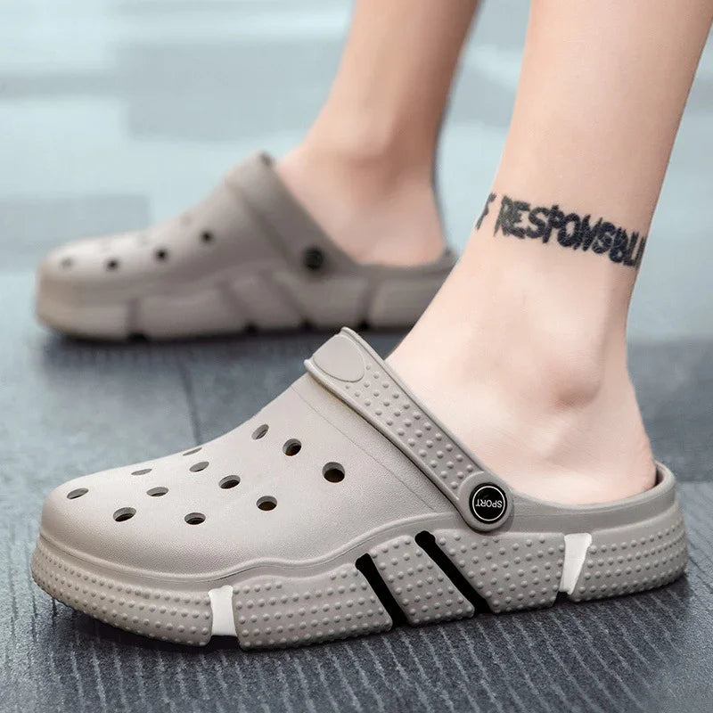 Gray casual sport clogs with ventilation holes worn on feet on a textured dark floor