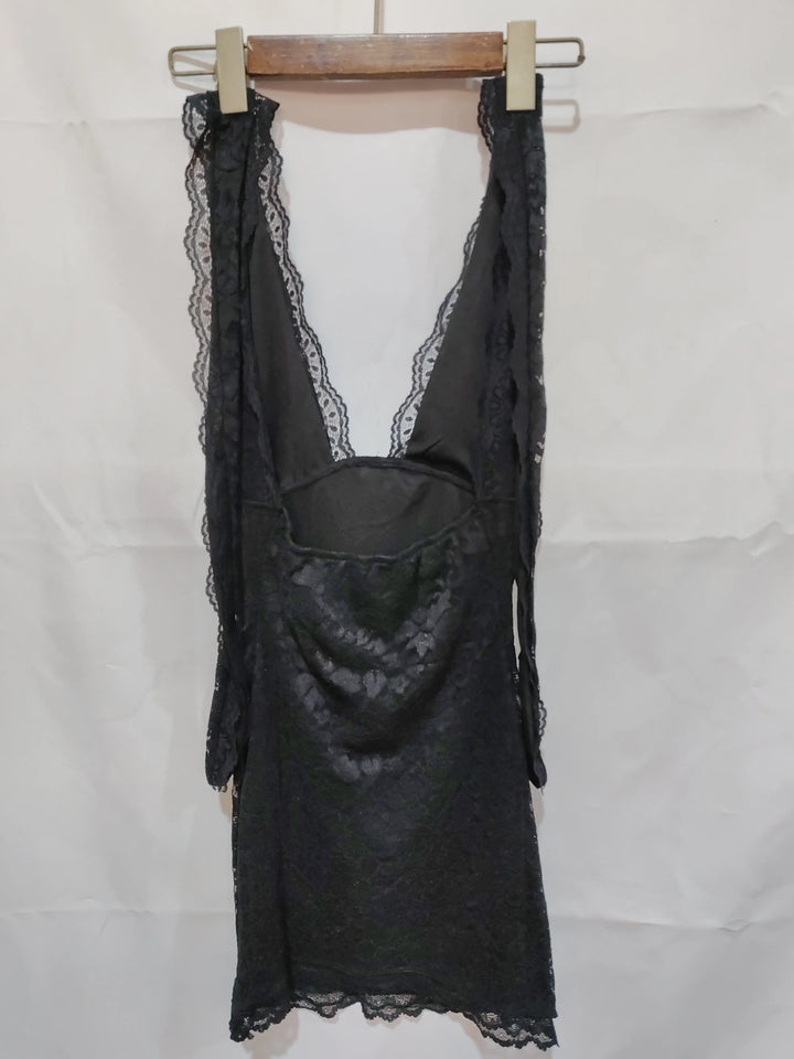 Black lace slip dress with deep V-neck hanging on wooden hanger against white background