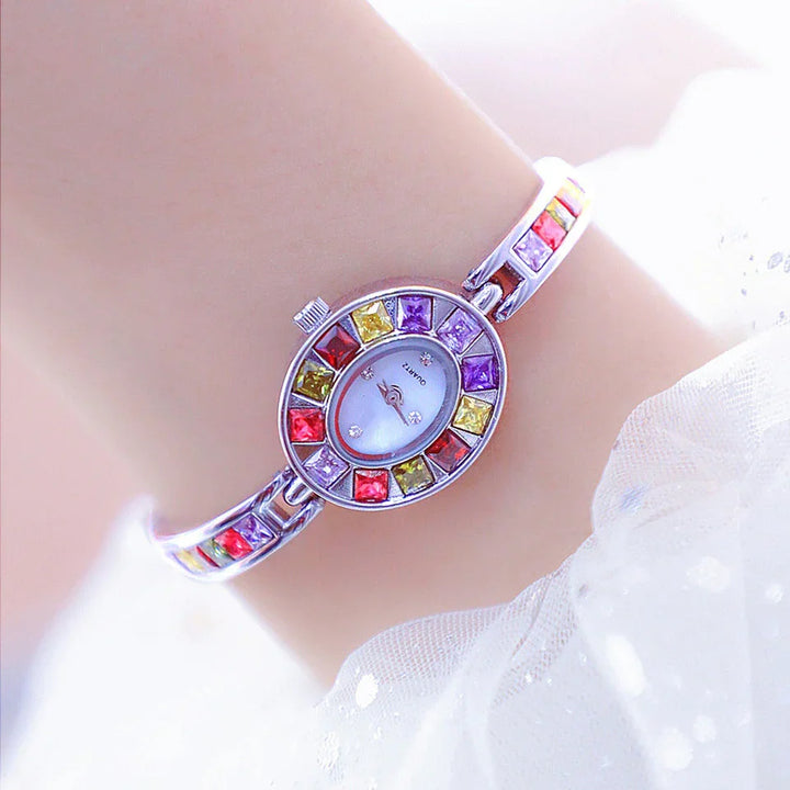 Close-up of silver quartz wristwatch with colorful square gemstones on band and bezel