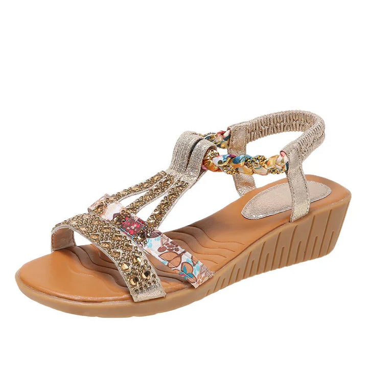 Beige wedge sandal with embellished straps and colorful floral accents, cushioned footbed