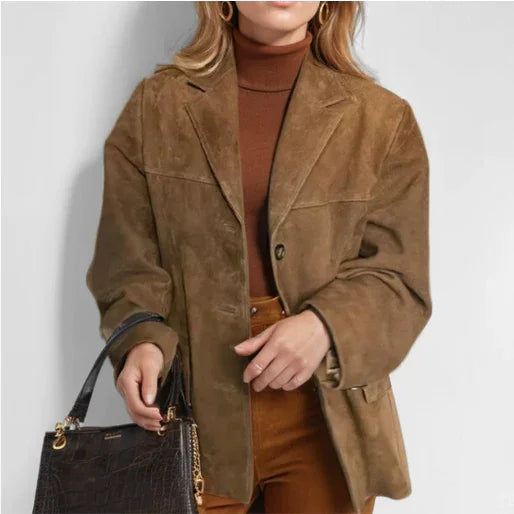 woman wearing brown suede blazer and turtleneck sweater holding black leather handbag