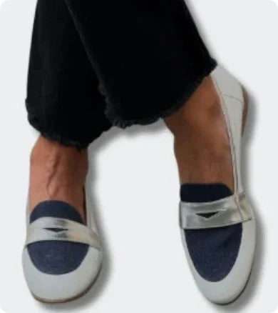 Close-up of feet wearing white and navy blue casual loafers with black pants