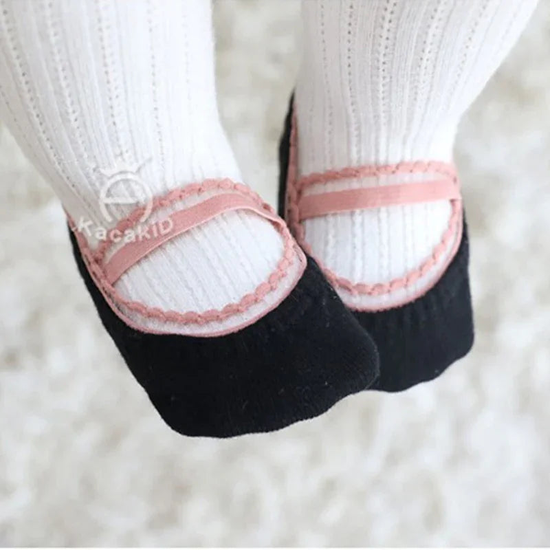 Close-up of baby feet wearing black and pink Mary Jane style socks with white ribbed tights