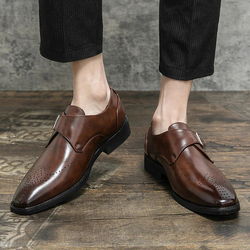 Men's brown leather monk strap dress shoes with perforated toe detail on wooden floor