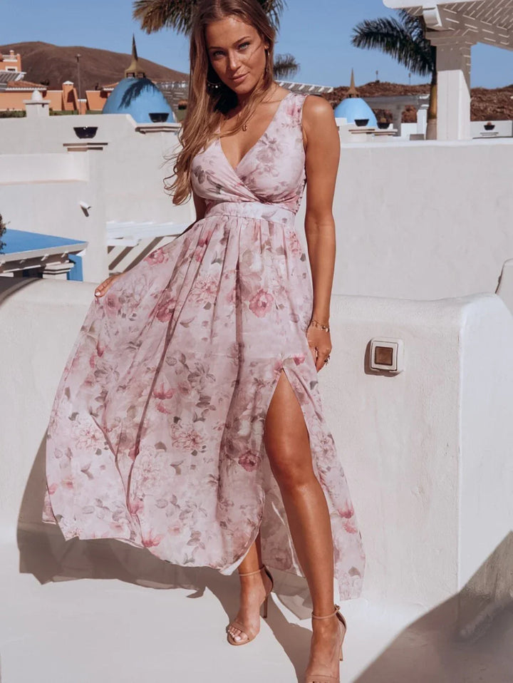 Woman wearing sleeveless floral midi dress with side slit posing outdoors in sunny Mediterranean setting