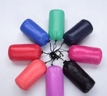 Colorful compressible travel pillows in red, blue, green, black, pink, and purple arranged in a circle on white background