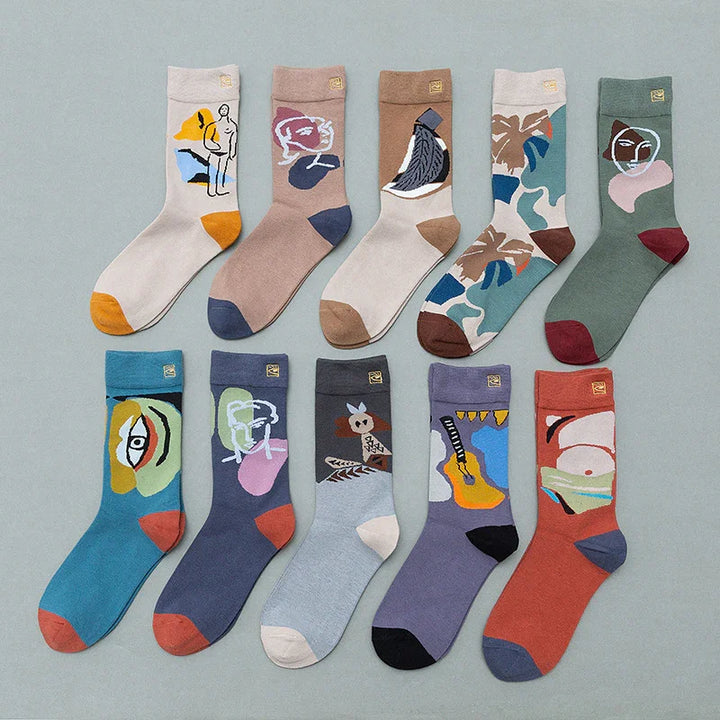 Ten pairs of colorful artistic socks with abstract faces and nature designs, arranged in two rows on gray background