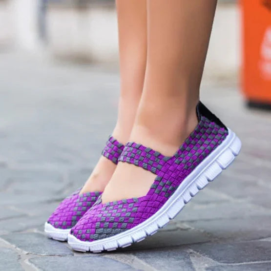 Woven purple and gray casual slip-on shoes with white flexible soles on paved ground