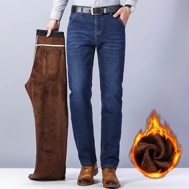 Man wearing blue jeans holding brown fleece-lined pants, warm winter denim with fire symbol