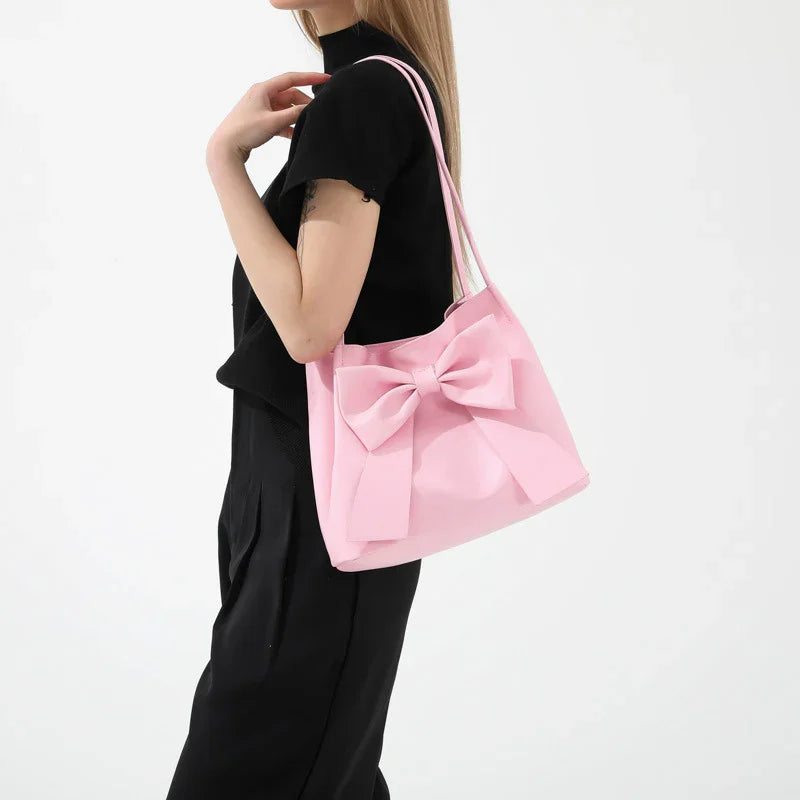 Woman in black outfit carrying a pink tote bag with a large bow detail on shoulder
