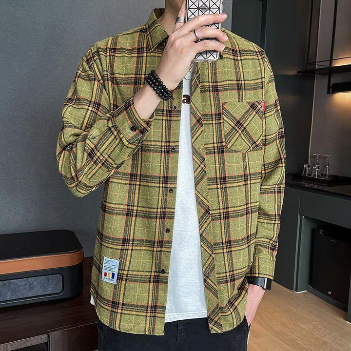 man wearing yellow plaid flannel shirt over white t-shirt taking mirror selfie in modern room