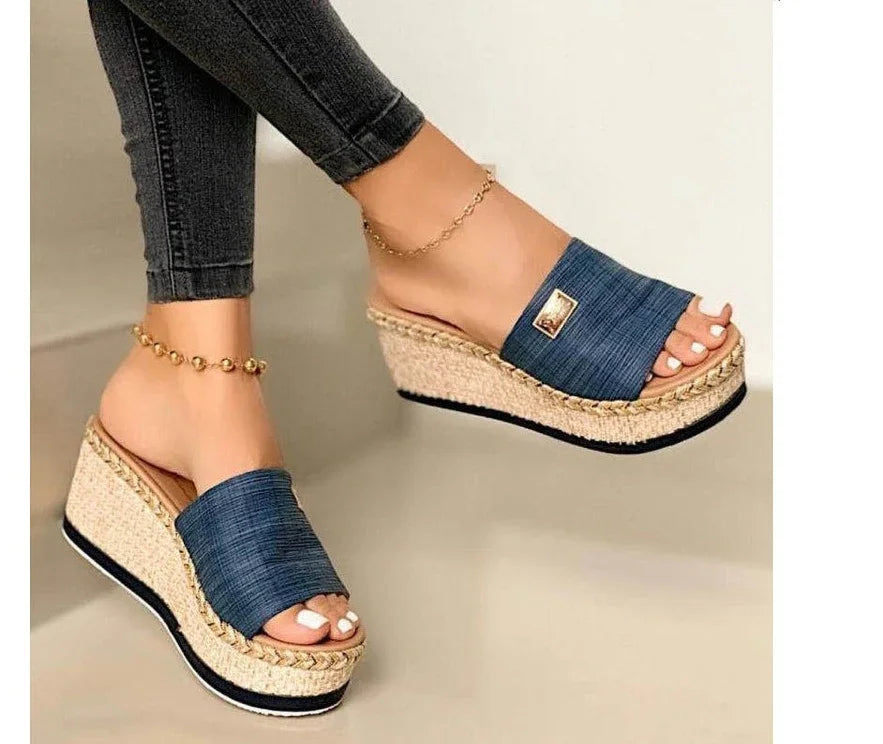 Woman wearing blue denim platform wedge sandals with braided jute sole and ankle bracelets
