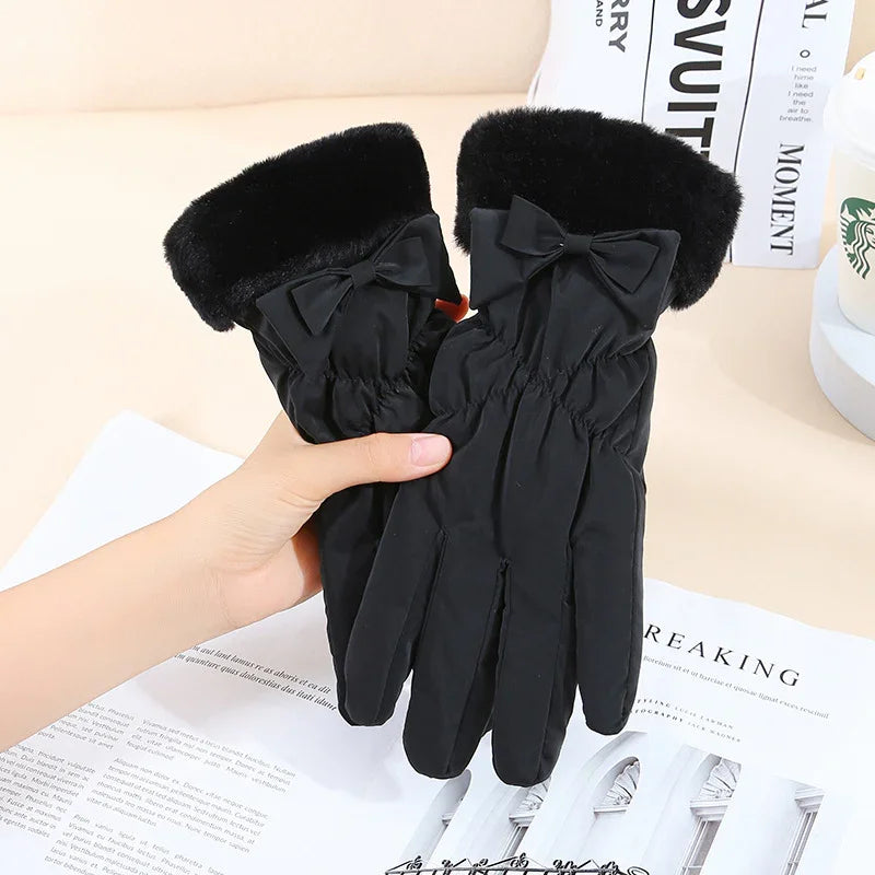 Black winter gloves with faux fur cuffs and decorative bows, held above magazine pages