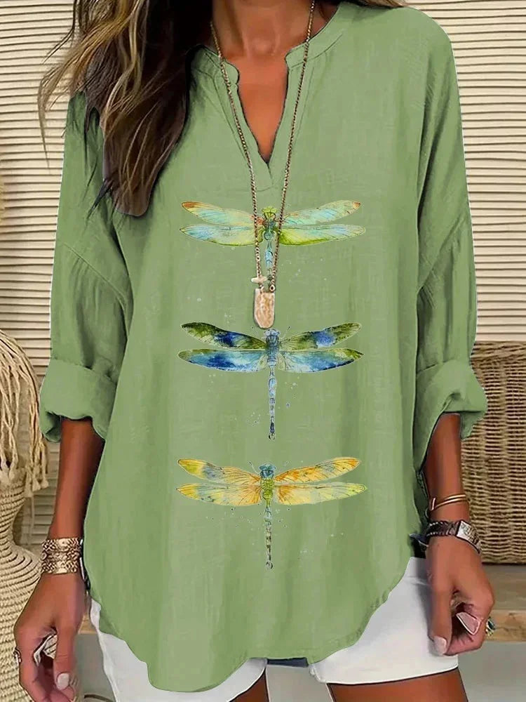 Woman wearing light green long sleeve shirt with three colorful dragonfly prints and white shorts