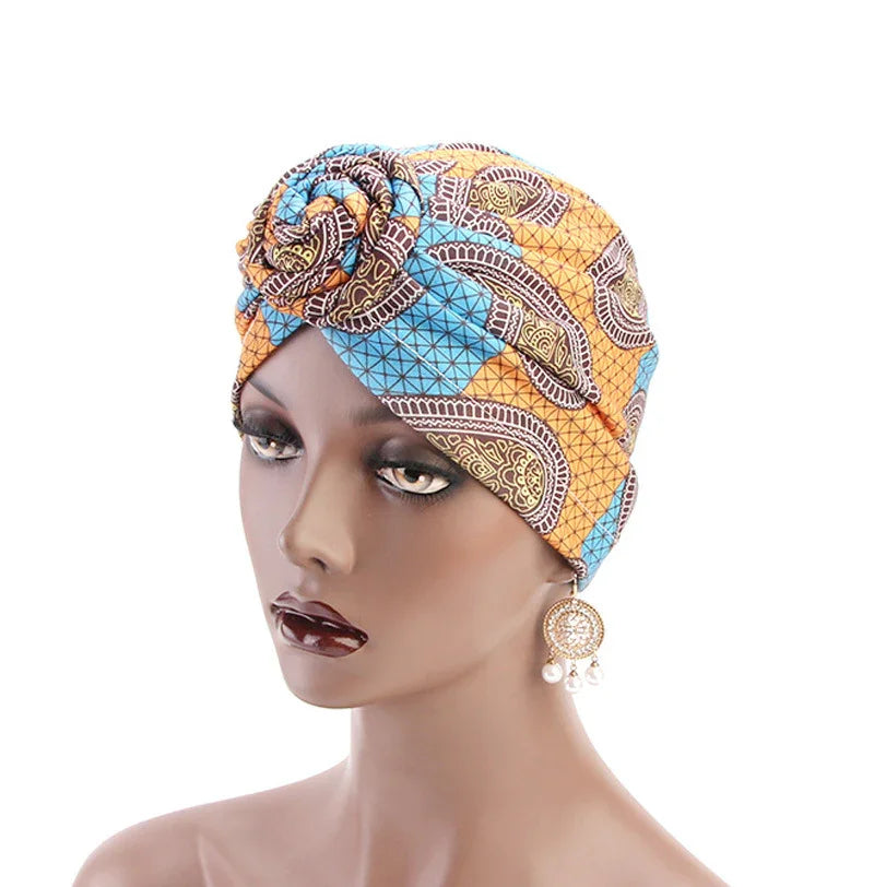 Woman mannequin wearing colorful African print turban headwrap with paisley patterns and decorative earrings