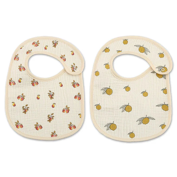 Two cream-colored baby bibs with snap closures, one with peach print, the other with orange print